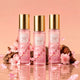 Japanese Cherry Blossom Body Mist 3-piece set with pink fragrance mist bottles, cherry blossoms, petals, and glossy reflection
